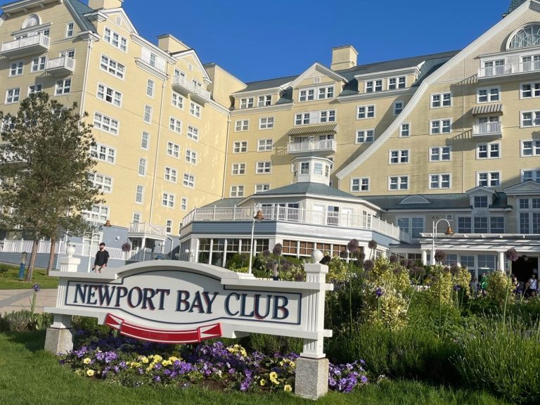 Exterior view of the Newport Bay Club with landscaped gardens and a blue sky.
