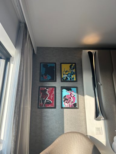 Four framed artwork pieces featuring bold colours, displayed on a grey wall.