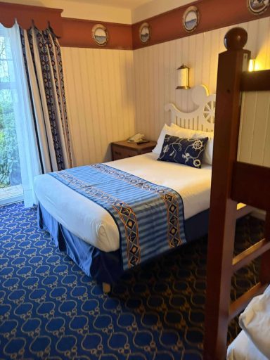 Space around the double bed A cosy hotel room with a double bed, patterned bedding, and blue decor.