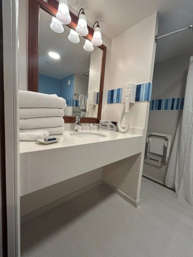Bathroom sink Modern bathroom with clean white sink, stacked towels, and shower area.