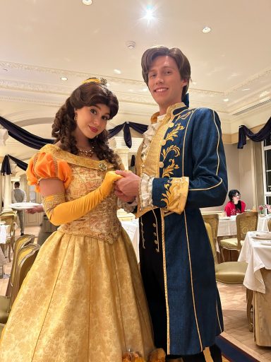 A woman in a yellow gown and a man in a blue coat pose together in a banquet setting.