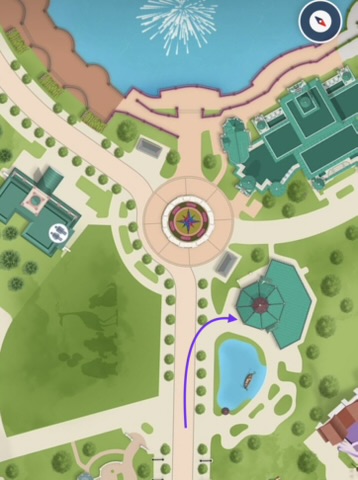 Map showing location of ride entrance Map view of a park layout featuring paths, a pond, and surrounding buildings.