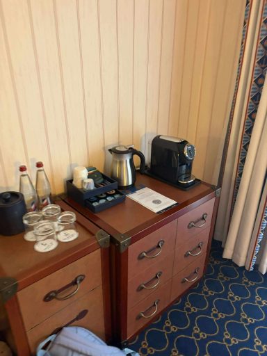 Tea and Coffee facilities Desk corner with two bottles of water, glasses, coffee maker, and a teapot.