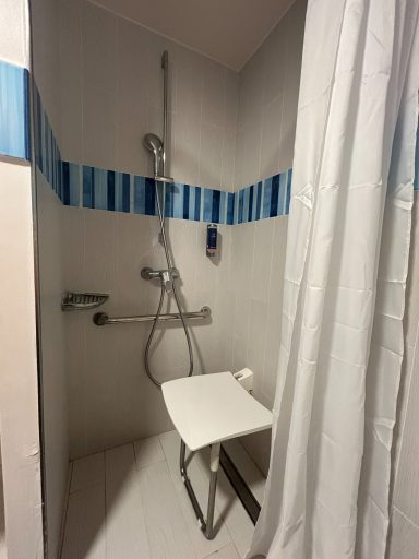 Accessible shower A shower with a folding seat and grab rails, featuring blue stripe decor.