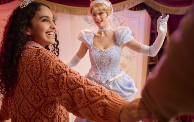 A young girl smiles as she interacts with a princess in a sparkling gown.