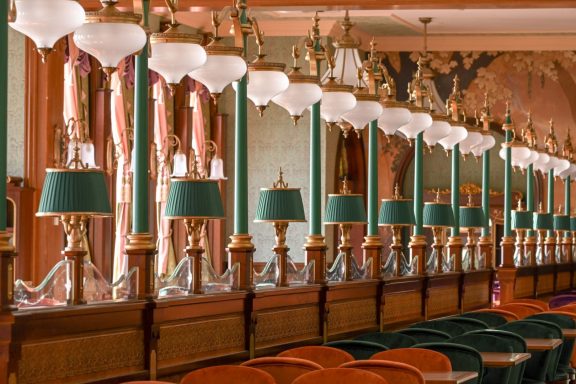 Elegant interior with vintage lamps and green shades, lined along a wooden counter.
