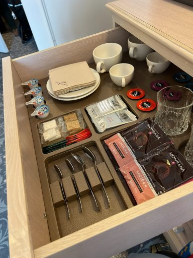 Organised drawer containing cups, plates, cutlery, and various food items.