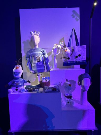 Display of frozen merchandise, including clothing and plush toys, under purple lighting.