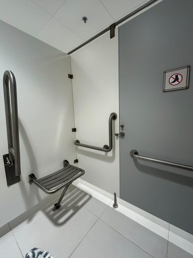 Accessible bathroom stall with grab bars and a fold-down bench.
