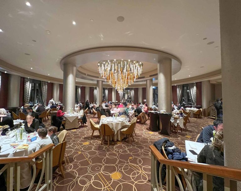 Elegant restaurant interior with round tables and a prominent chandelier.