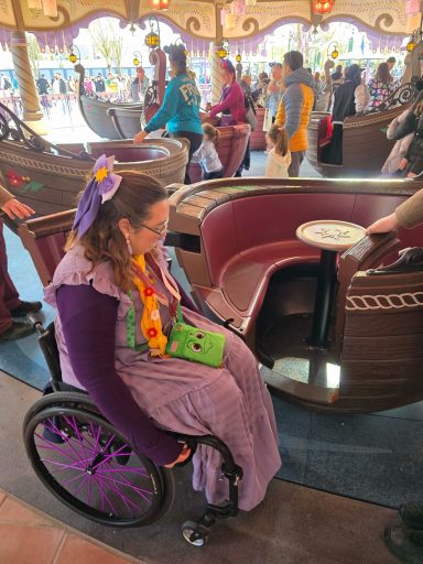 Access for side transfer A woman in a wheelchair examines a ride vehicle at a theme park.