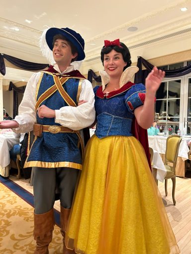 Snow White and a prince in costume, smiling at a festive event.