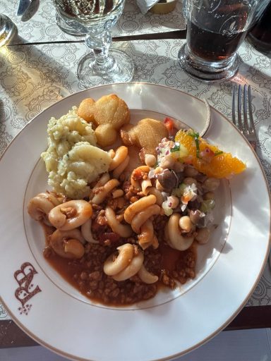 Plate of food featuring shrimp, vegetables, and a citrus garnish, with potatoes on the side.