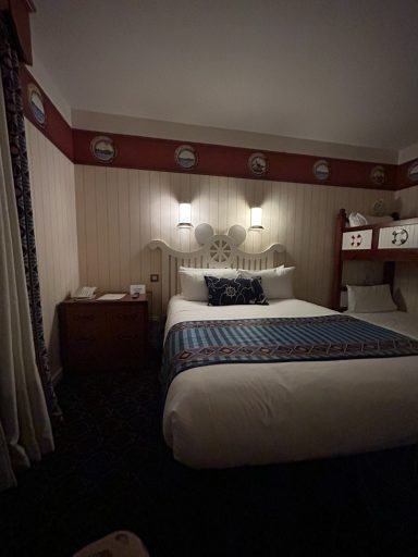 Accessible room - beds A compact hotel room featuring a double bed, bedside lamps, and a bunk bed.