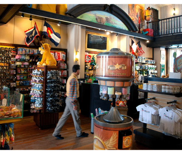 Interior of a gift shop featuring merchandise, a drink dispenser, and a customer browsing.