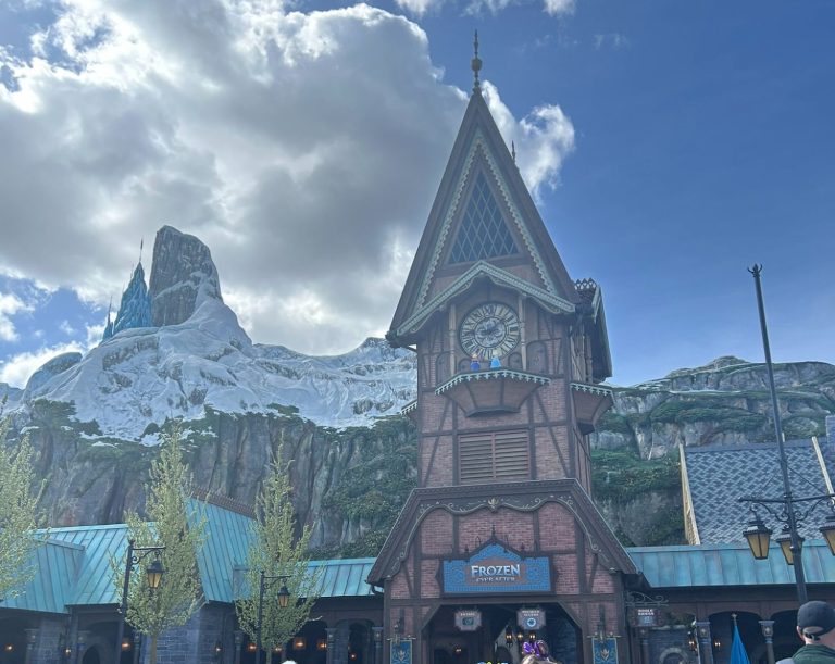 A tall, chalet-style building with a mountain backdrop and cloudy sky.