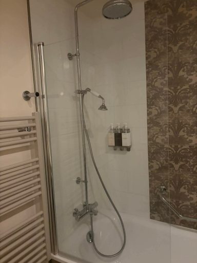 Shower area with a glass screen, rainfall showerhead, and tiled wall.