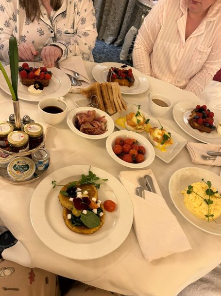 A table set with various dishes, including pancakes, fruit, and sauces.