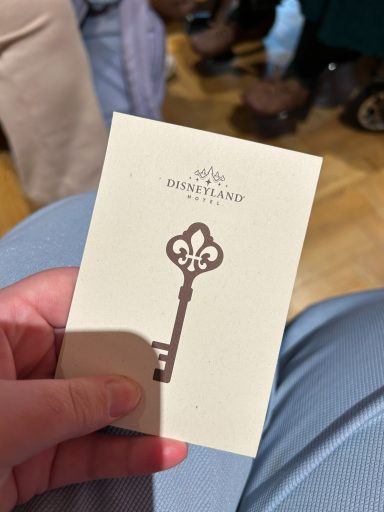 A hand holding a card with a key illustration and "Disneyland" logo.