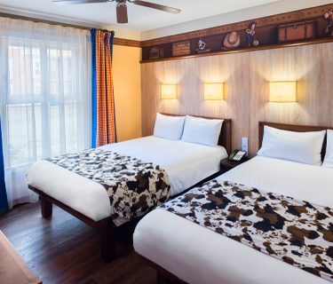 A cosy hotel room featuring two beds, wooden decor, and soft lighting.