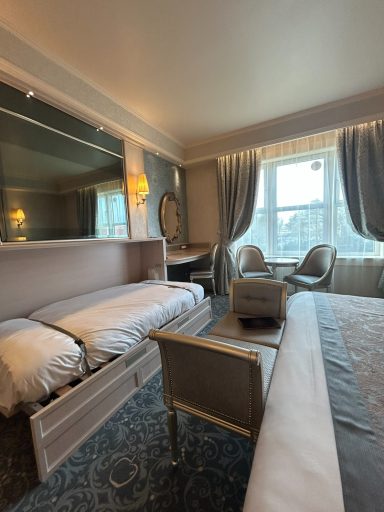 Modern hotel room with a double bed, elegant decor, and large windows letting in natural light.