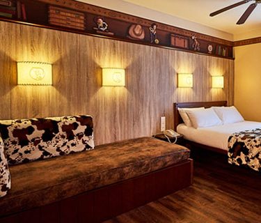 Modern hotel room with a bed, a seating area, and decorative wall lights.