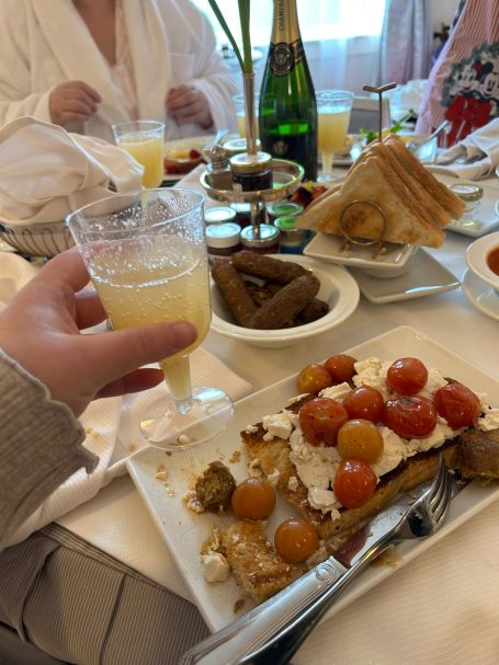 a plate of half eaten tofu scramble on toast with a plastic champagne flute held up in the foreground