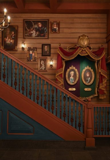 Staircase with wooden panelling, portraits on the wall, and decorative banners.