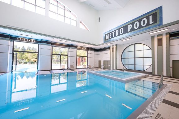 Indoor swimming pool with clear blue water and large windows allowing natural light.