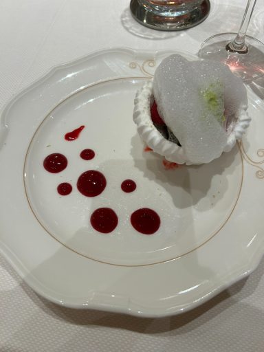 Dessert served in a white bowl, garnished with raspberry sauce droplets.