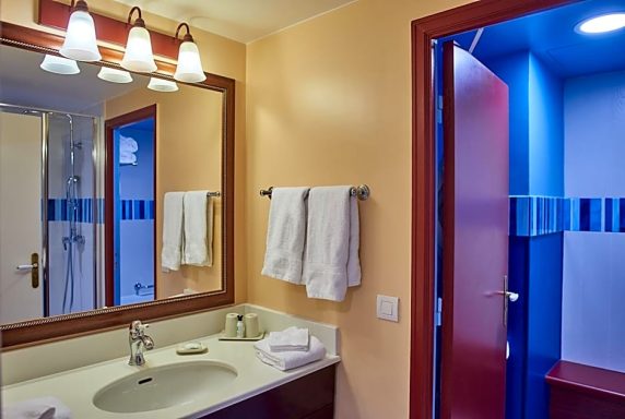 Modern bathroom featuring a sink, mirror, and towels, with blue accent lighting.