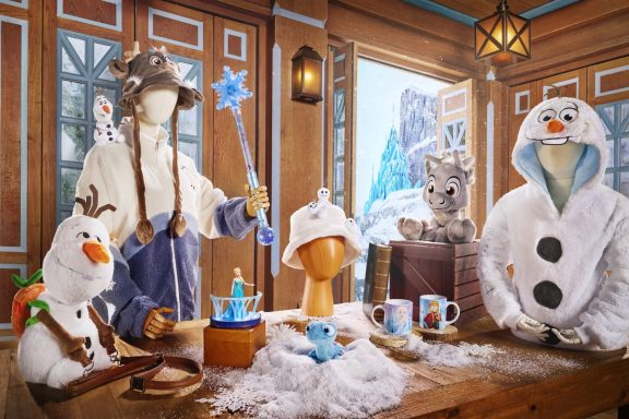 A whimsical winter scene featuring plush characters and themed merchandise on a snowy table.